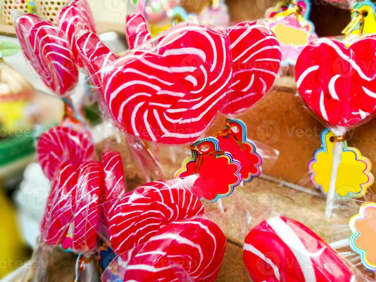 Closeup and crops colorful sweet lollypops with labels for sale on wooden shelf background. photo