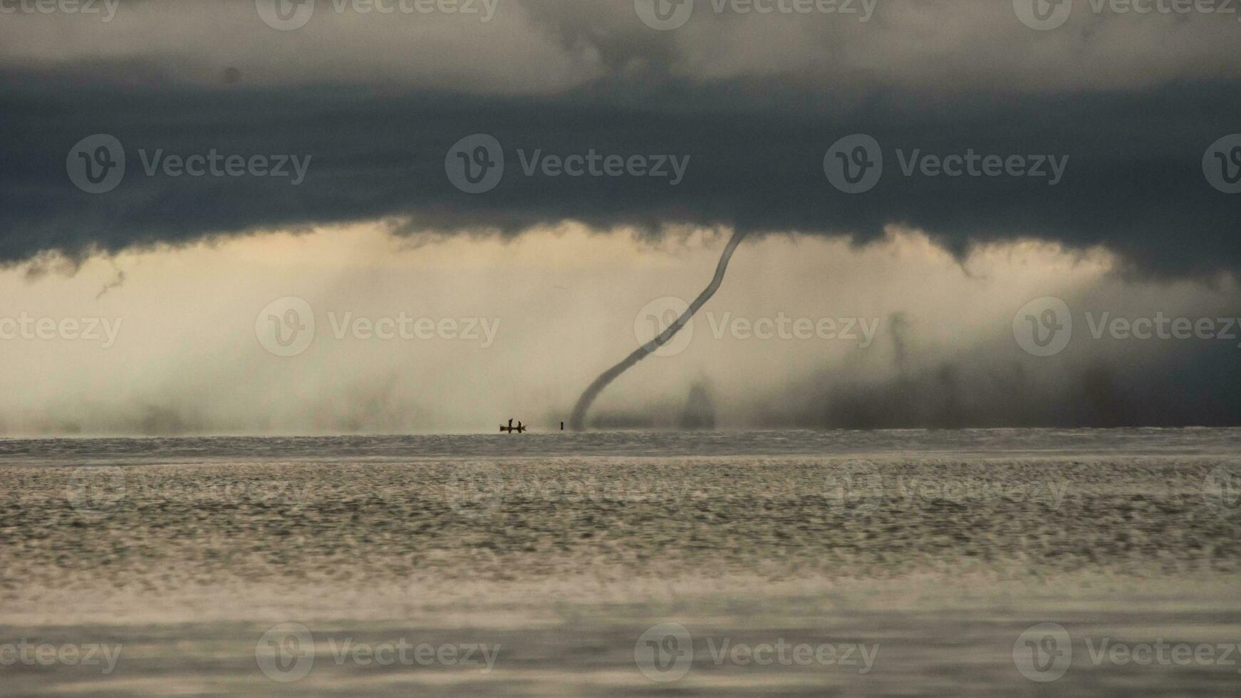 Tornado hitting the water from a clouded sky photo