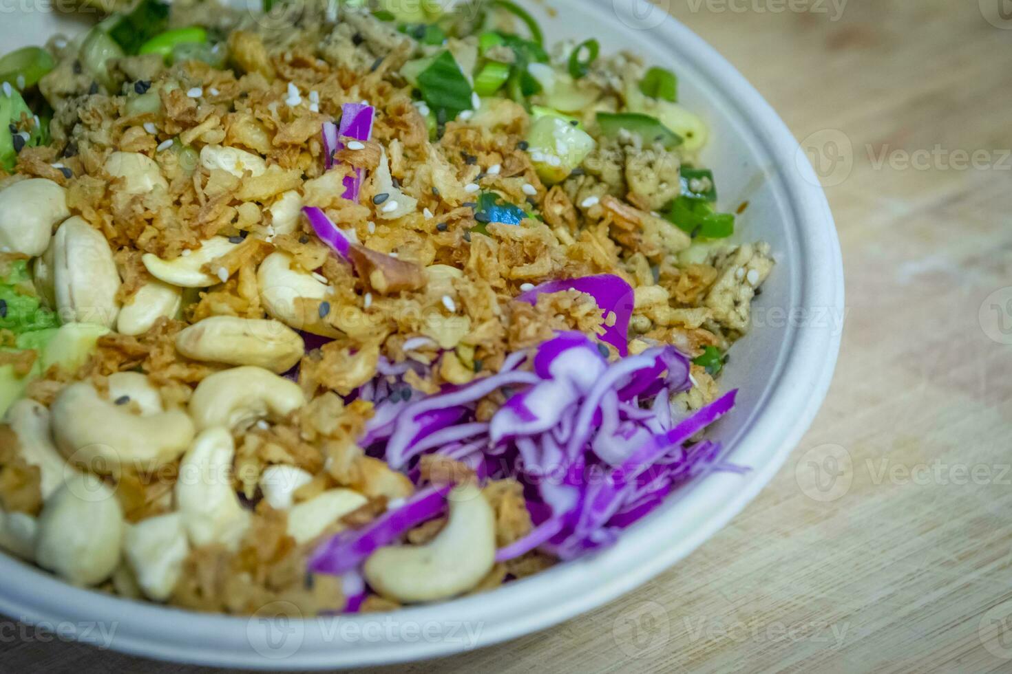 Vegan poke bowl with cashew nuts, red cabbage, dried onions, avocado and much more ingredients photo