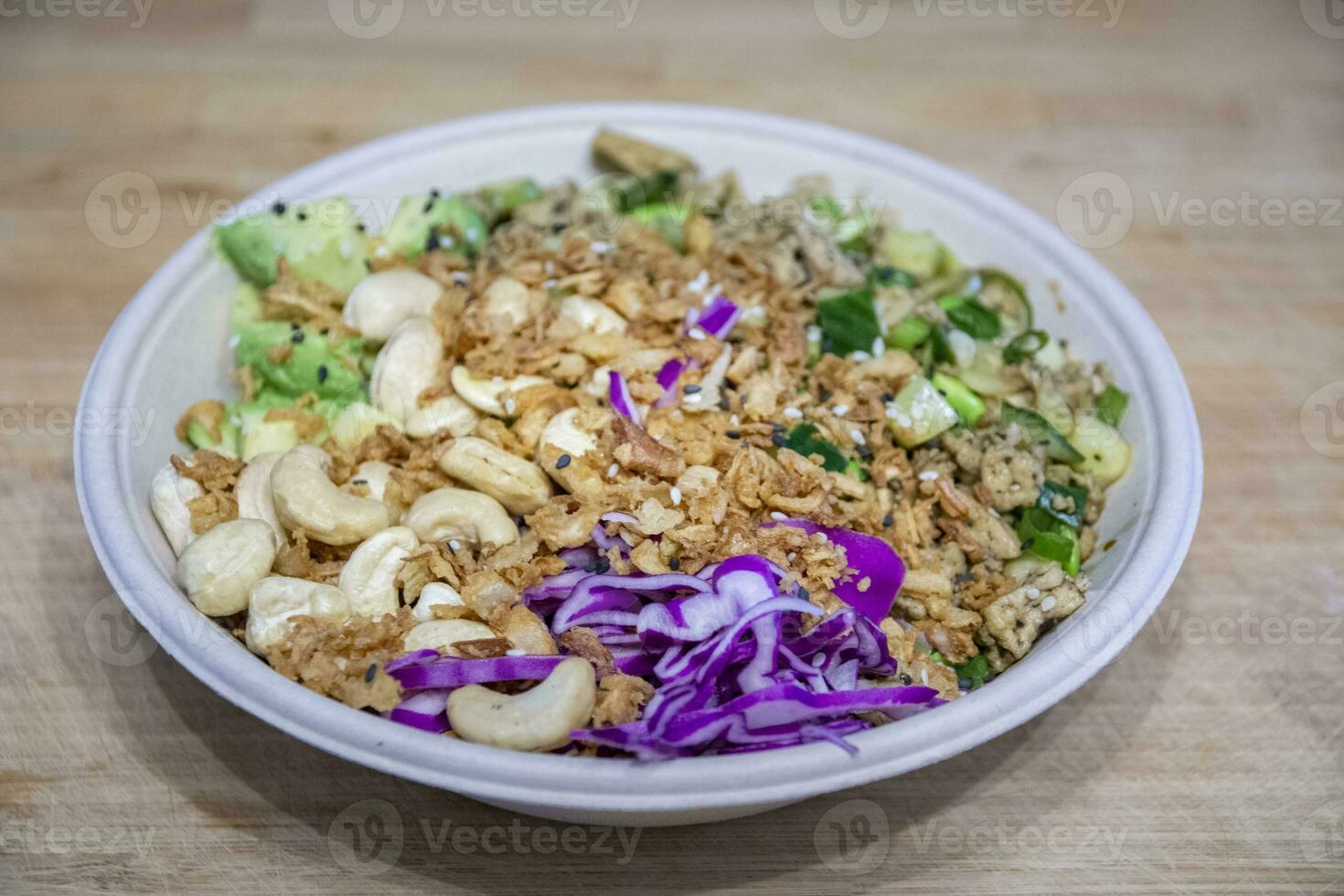 Vegan poke bowl with cashew nuts, red cabbage, dried onions, avocado and much more ingredients photo