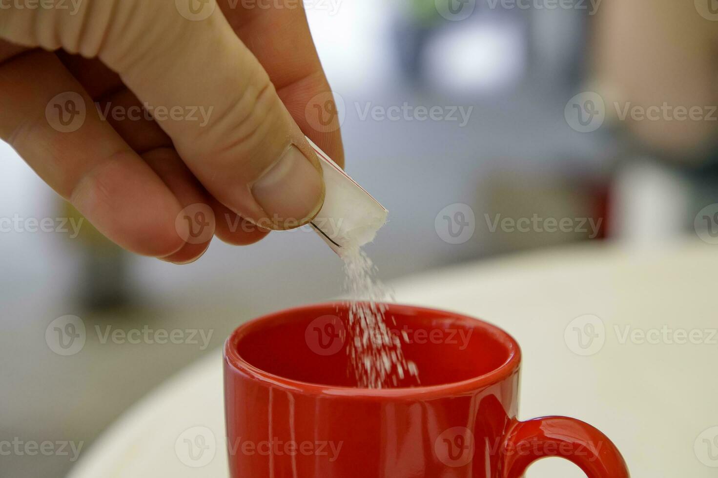 hand putting sugar in a cup of coffee or tea. Close photo