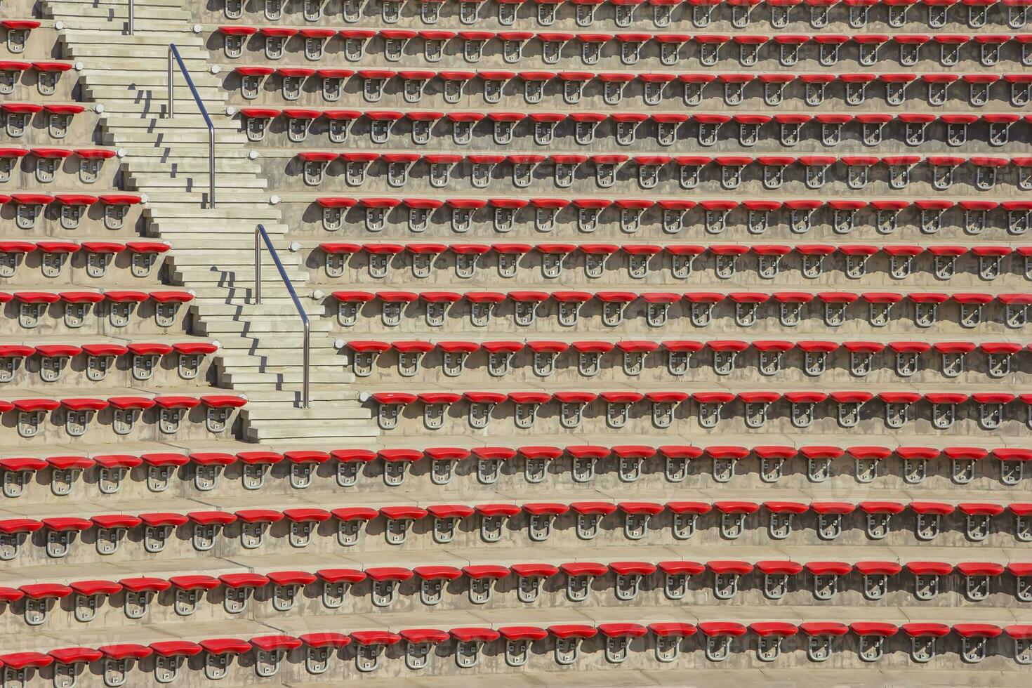 Empty red plastic chairs in the stands of the stadium or amphitheater. Many empty seats for spectators in the stands. photo