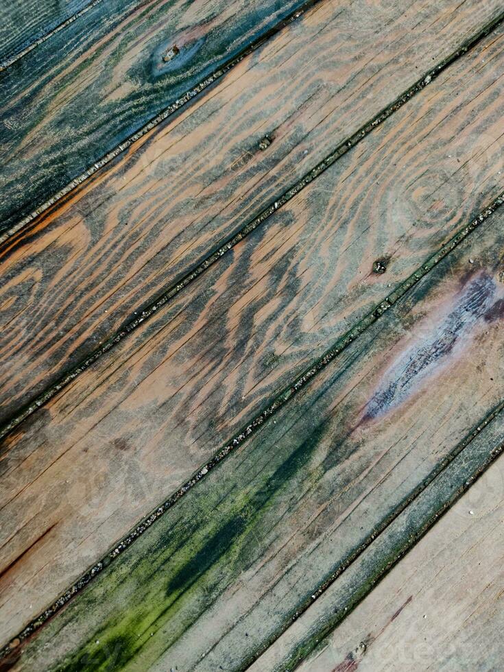 Background of wood coating made of boards with multicolored spots from humidity, diagonal lines, top view, close-up. photo