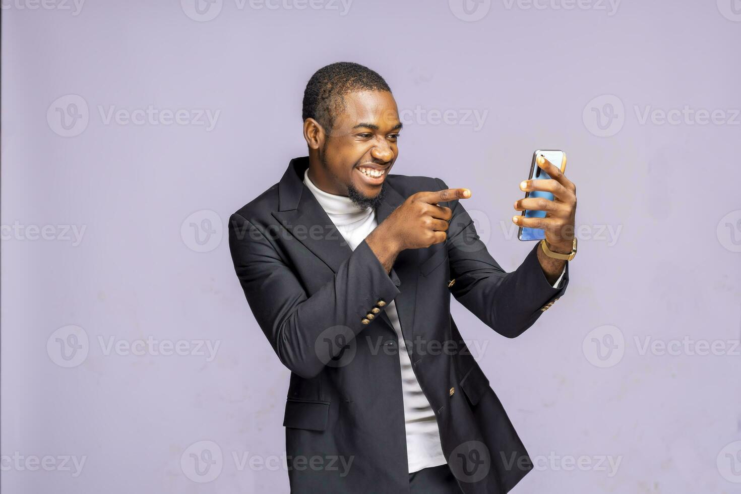 happy ecstatic african businessman on suit looking, pointing at cell phone celebrate receiving reading good news isolated on a white studio background photo