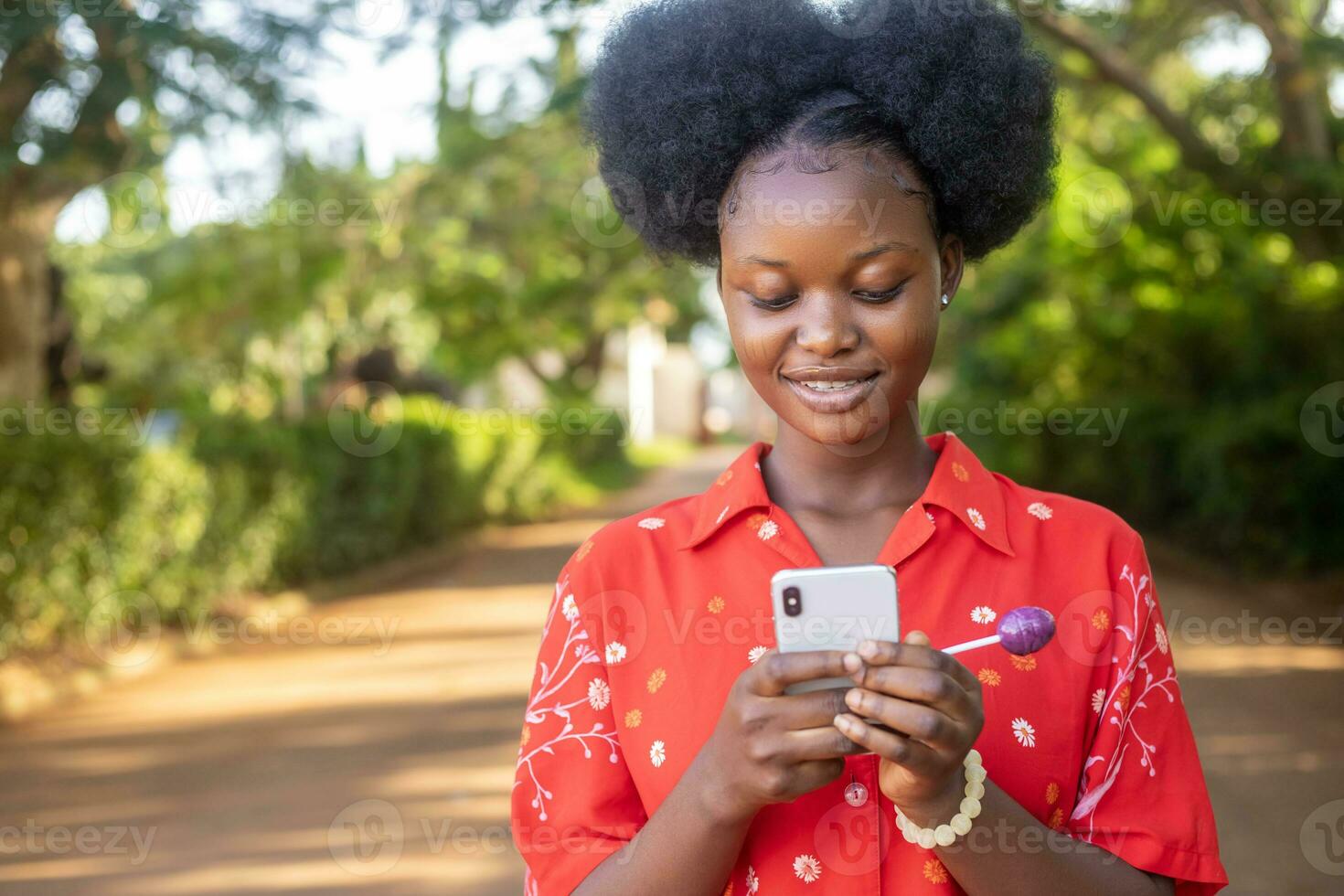 pretty black woman look very excited and rejoices while looking at her phone photo