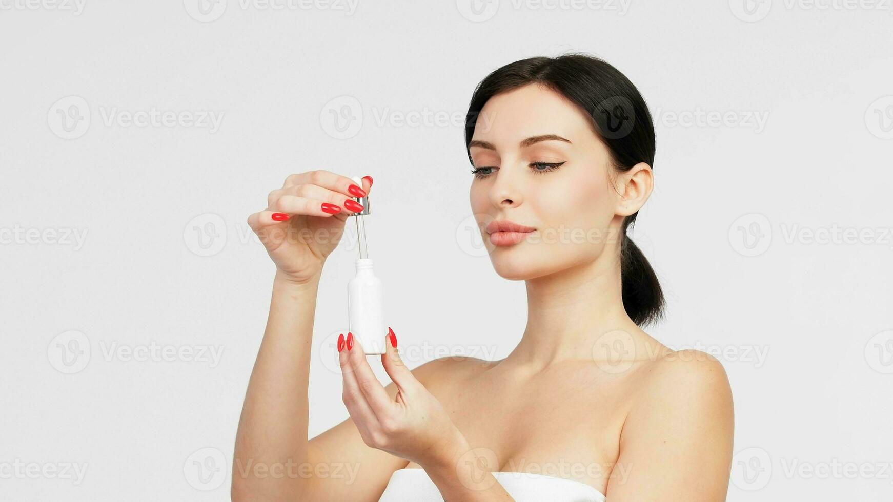 Closeup beautiful woman with perfect natural skin hold mockup tube face serum for skincare treatment product advertising expressive facial and gesture expression in isolated background. photo
