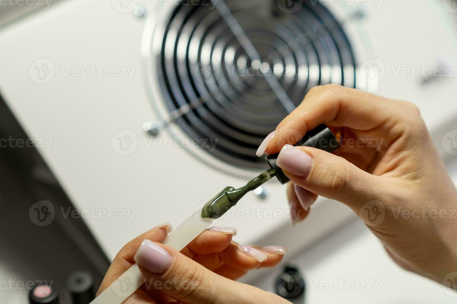 A manicurist applies gel nail polish to empty tips as a sample photo