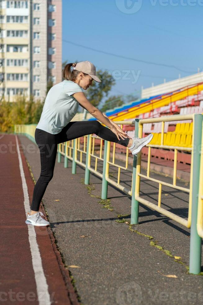 A young beautiful woman in sportswear plays sports at a local stadium photo