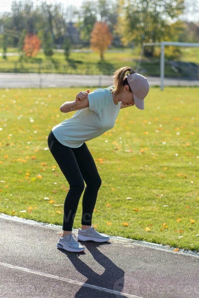 A young beautiful woman in sportswear plays sports at a local stadium photo