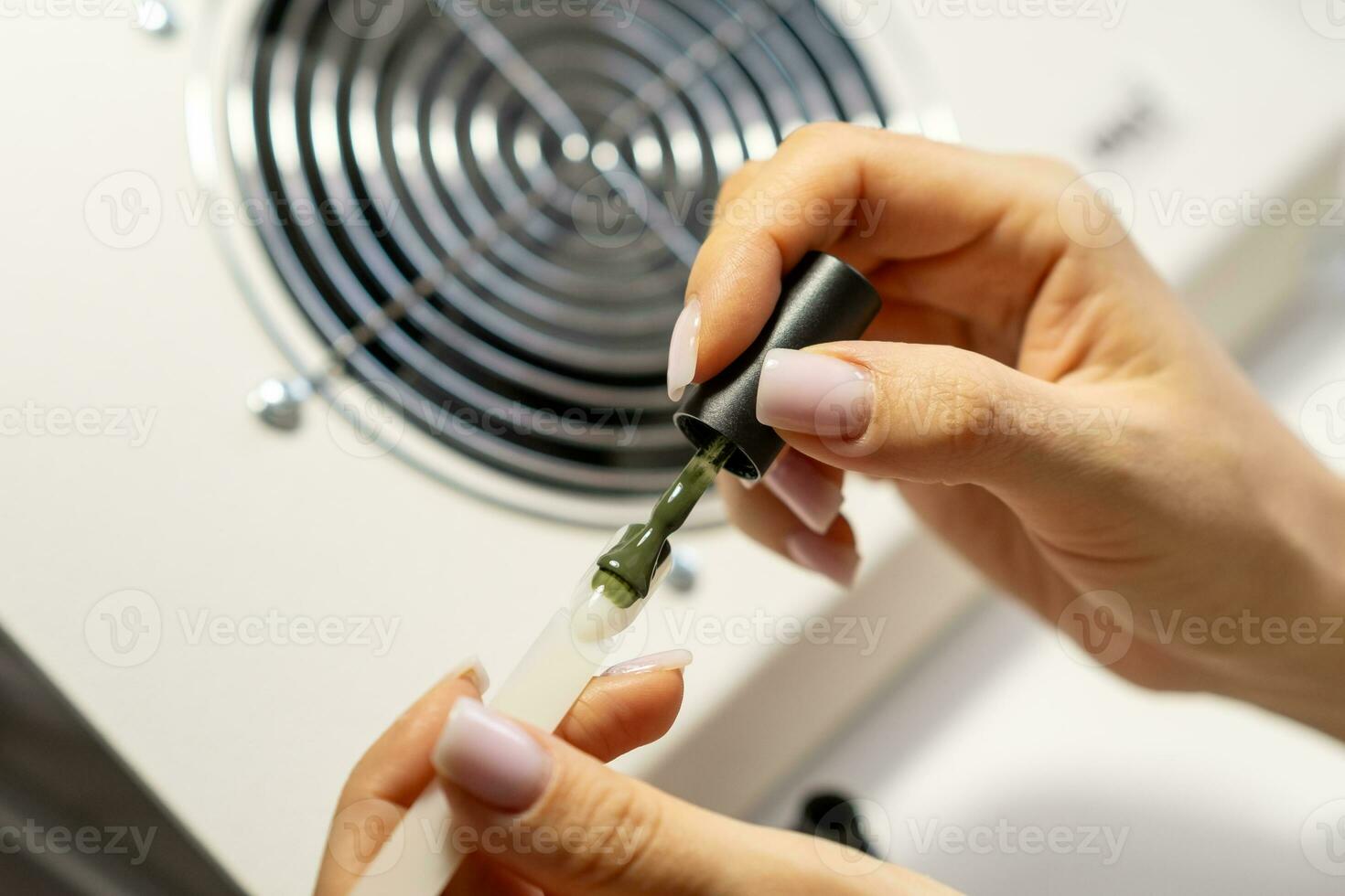 A manicurist applies gel nail polish to empty tips as a sample photo