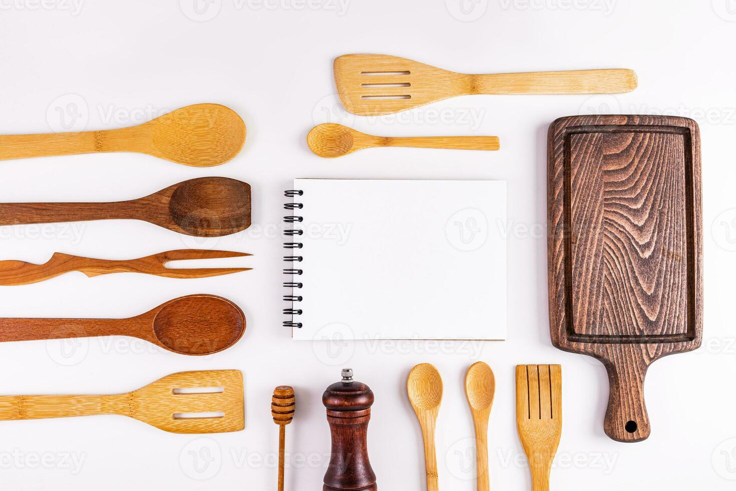 A blank page of a notebook, a recipe book among wooden kitchen utensils, a cutting board. Top view. Space for cooking text. Flat lay. photo