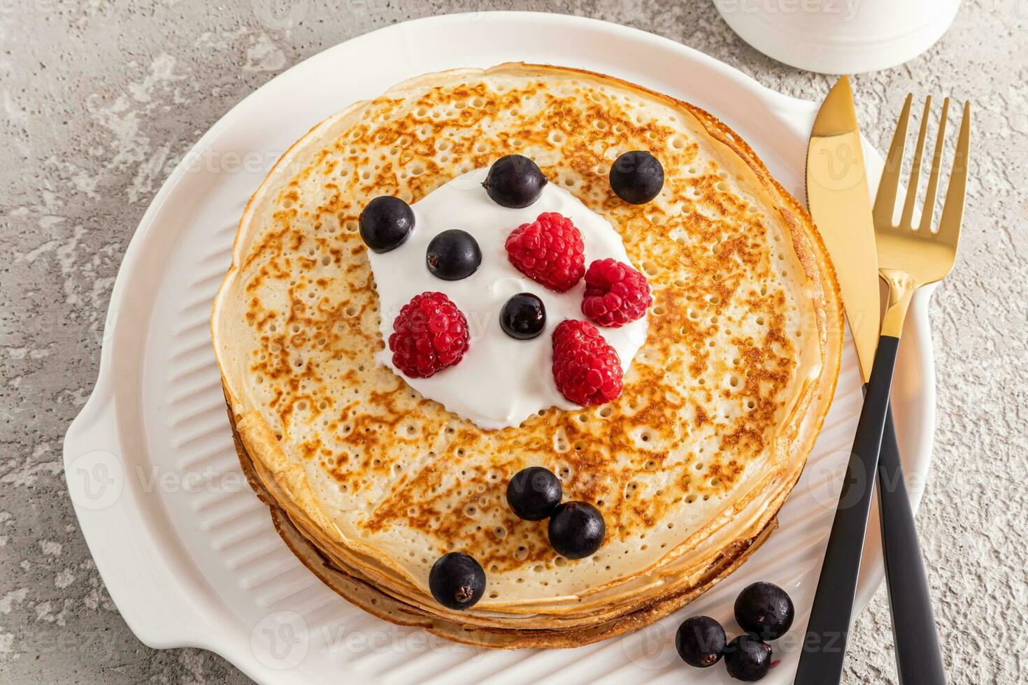 A large stack of delicious pancakes with sour cream and fresh berries on a white serving tray. Concept of traditional spring festival in Russia. photo