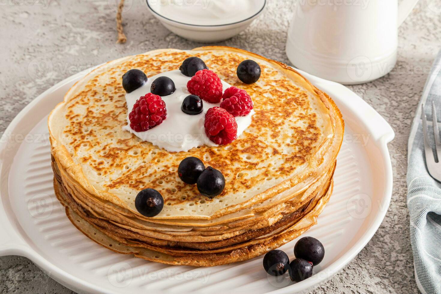 A large stack of delicious hot pancakes with sour cream and blackberries on a beautiful white serving tray. A traditional treat for the Festival photo
