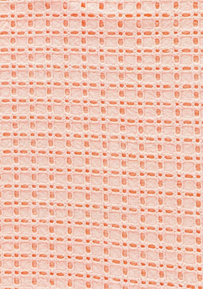 Textile background made of lace cotton fabric in peach color. Industry and Fashion trending Color of the Year . peach fuzz. Vertical view. photo