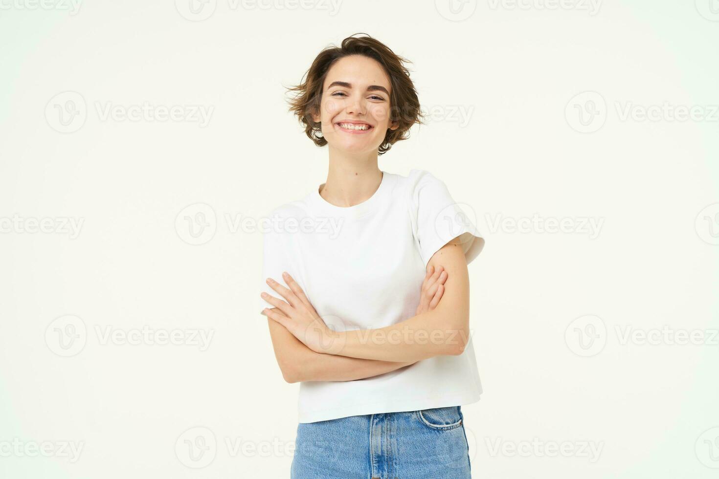 Portrait of cheerful woman laughing and smiling, cross arms on chest, standing in confident power pose, young professional concept, white studio background photo