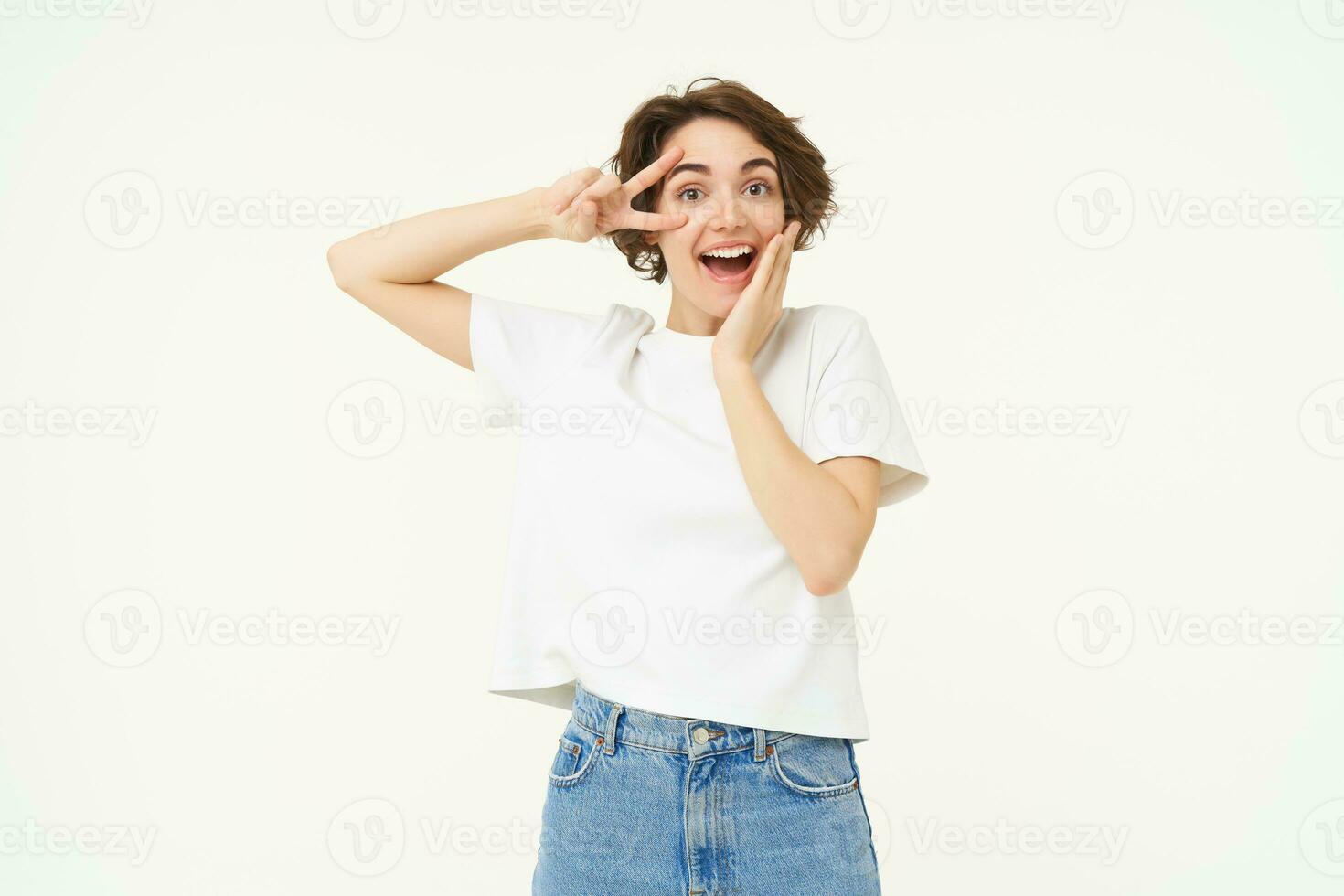 Portrait of happy and carefree woman, shows peace, v-sign gesture, having fun, posing for photo over white background