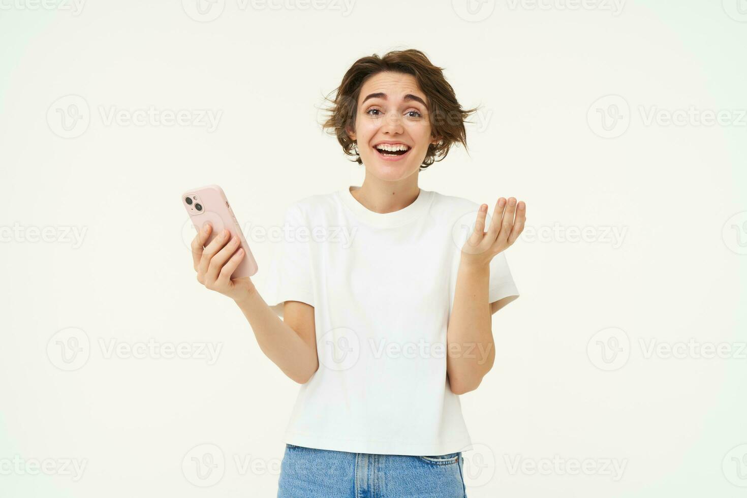 Technology and people. Happy brunette woman with mobile phone, smiling and laughing, standing over white background photo