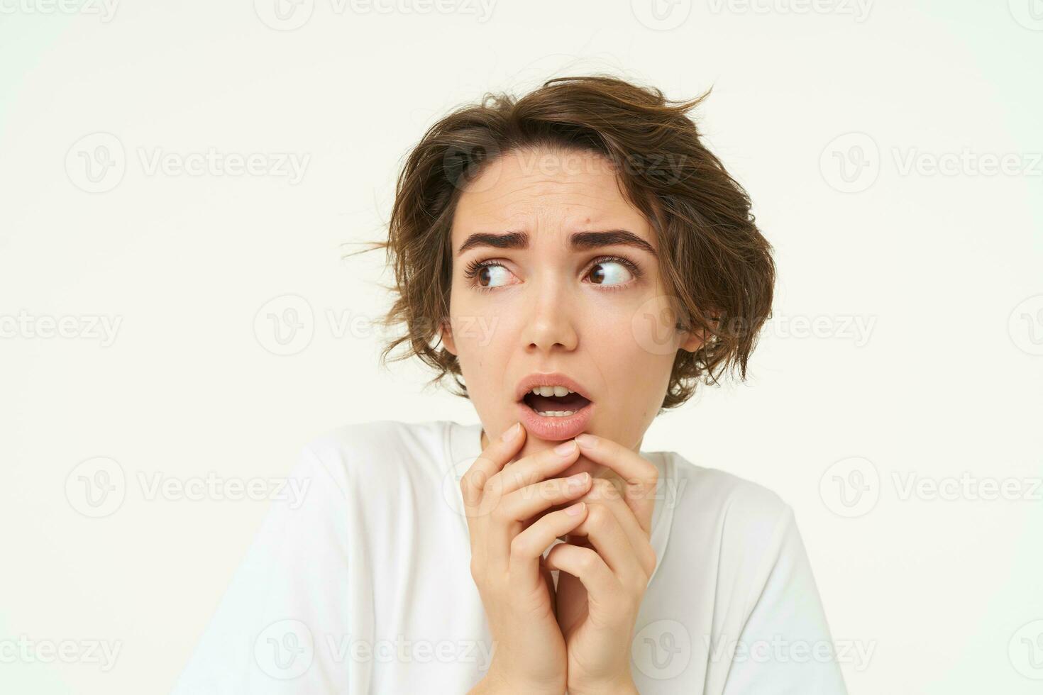 Close up of shocked, scared and worried young woman, trembling from fear, posing over white background photo