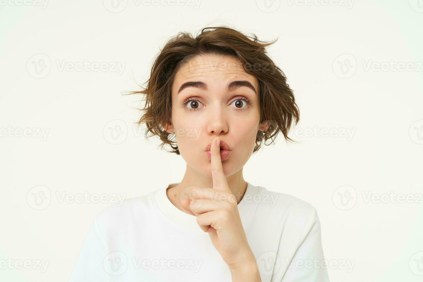 Close up shot of cute girl, press finger to lips, makes shhh shush noise, keeps secret, stands over white background photo