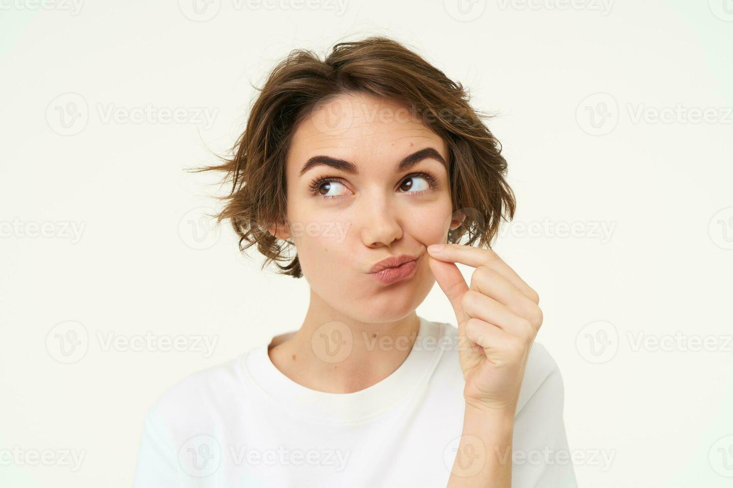 Image of young woman makes promise to keep secret, shows mouth zip gesture, puts a seal on her lips, dont talk sign, stands over white background photo