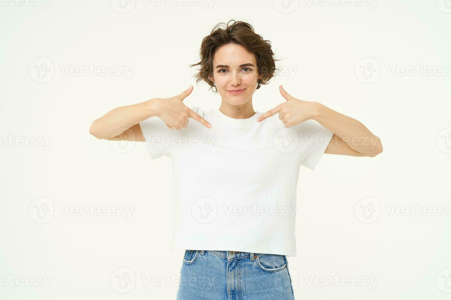 Image of confident, happy young woman, pointing at herself with smiling face, self-assured, standing over white background photo