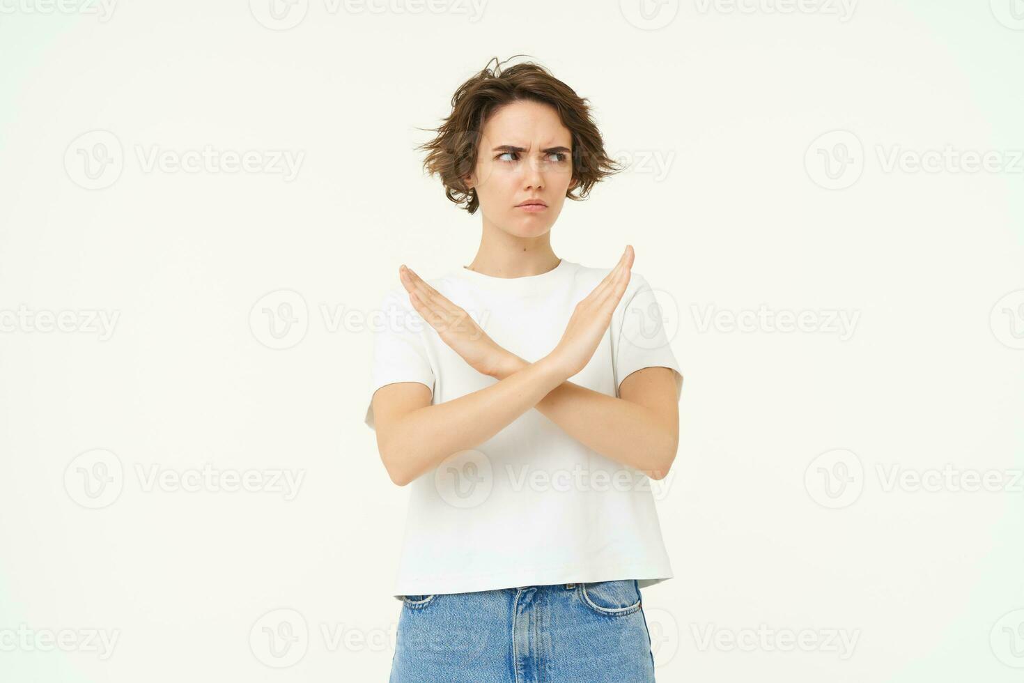 Image of woman expresses dislike, shows cross, stop gesture, disapprove something, prohibit, stands over white studio background photo