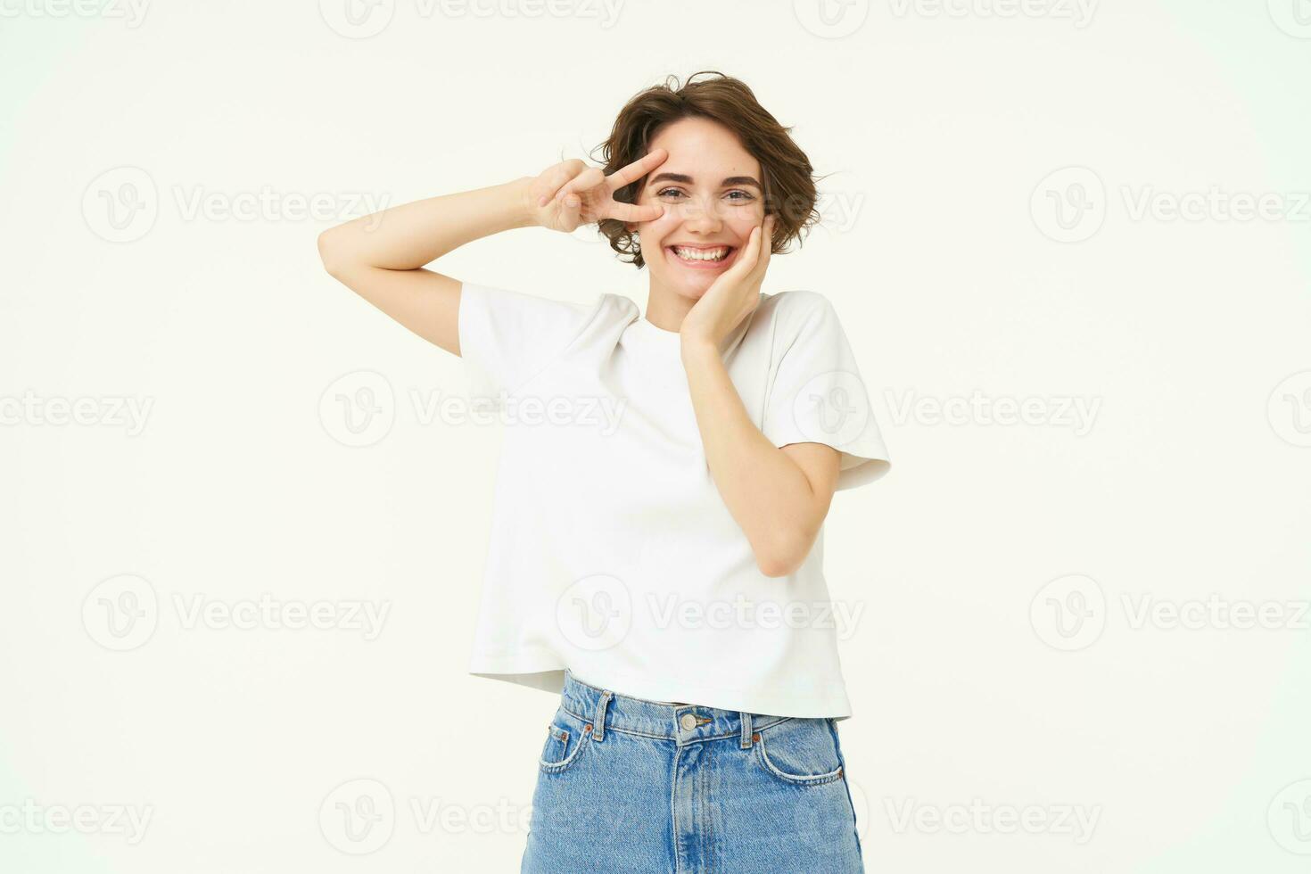 Portrait of happy and carefree woman, shows peace, v-sign gesture, having fun, posing for photo over white background