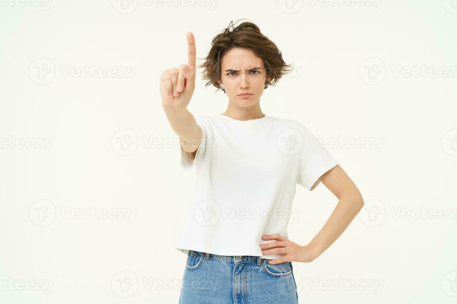 retrato de grave mujer muestra uno dedo, regla o tabú gesto, desaprobar algo, regaño persona, ceñudo a cámara, mirando enojado, en pie terminado blanco antecedentes foto