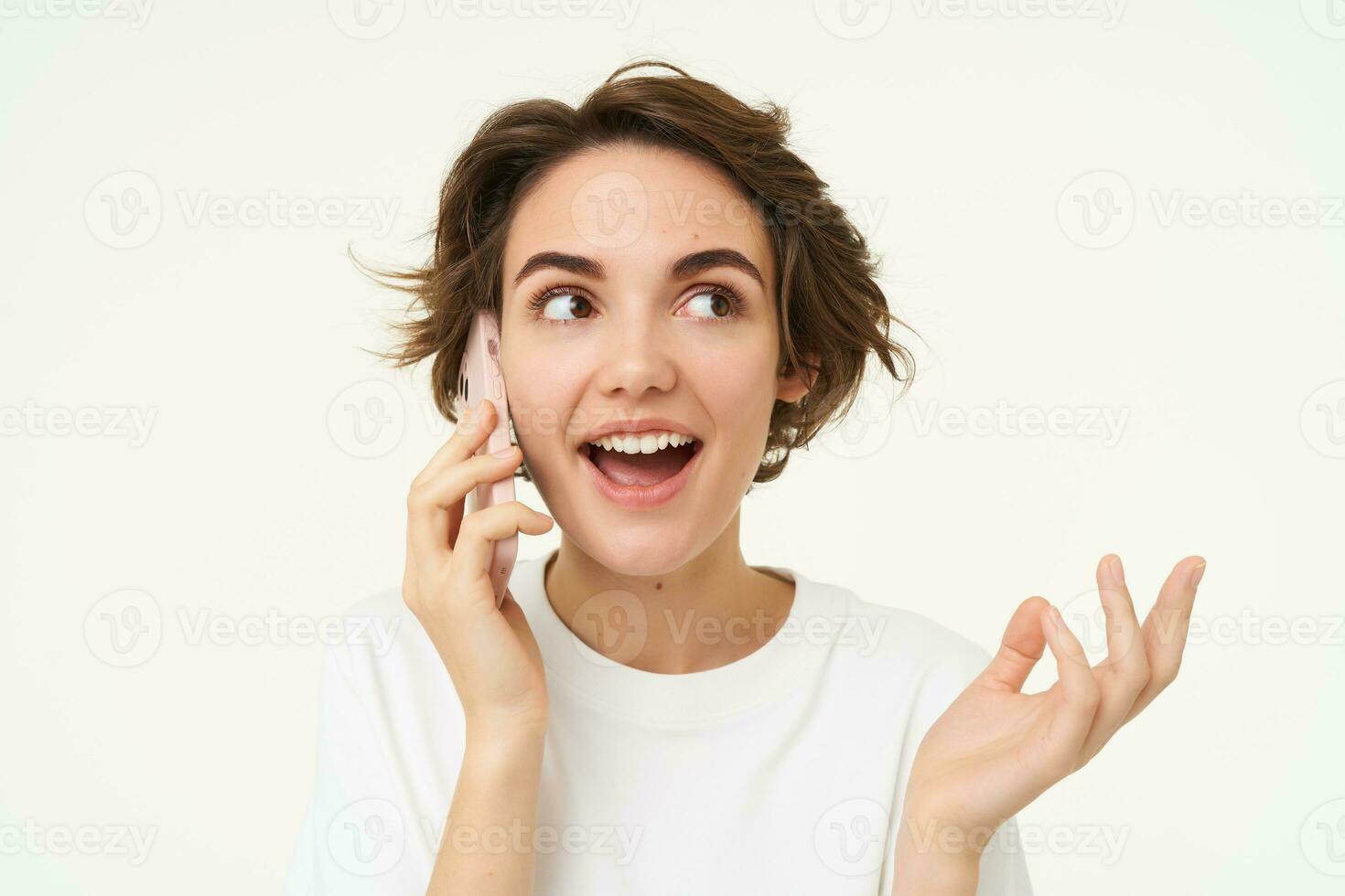 Portrait of happy, chatty young woman talking on mobile phone, using smartphone, calling someone, standing over white studio background photo