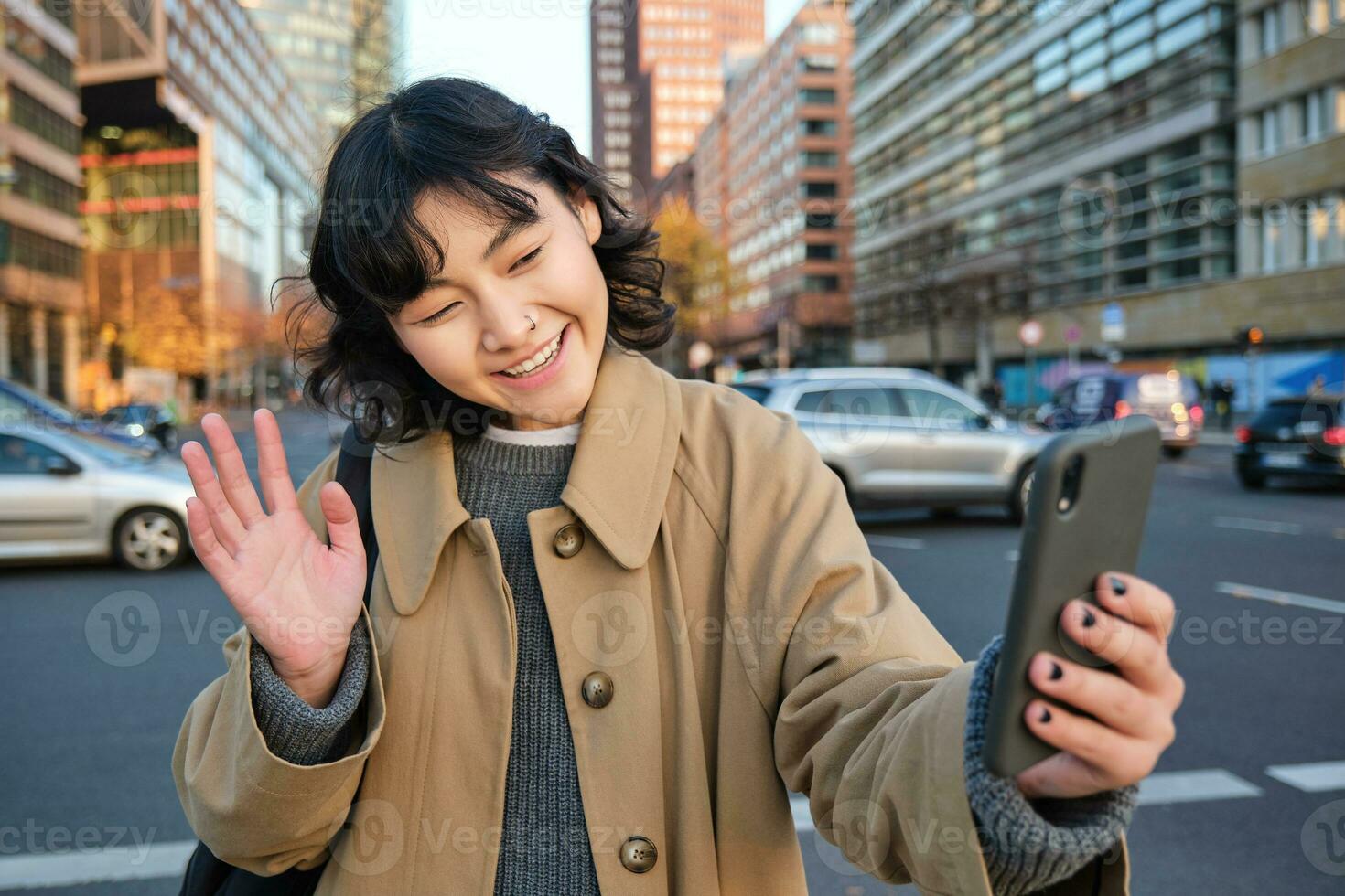 contento asiático niña turista, toma selfie en ciudad centro, hace vídeo llamada y olas a teléfono inteligente cámara, saluda alguien terminado teléfono foto