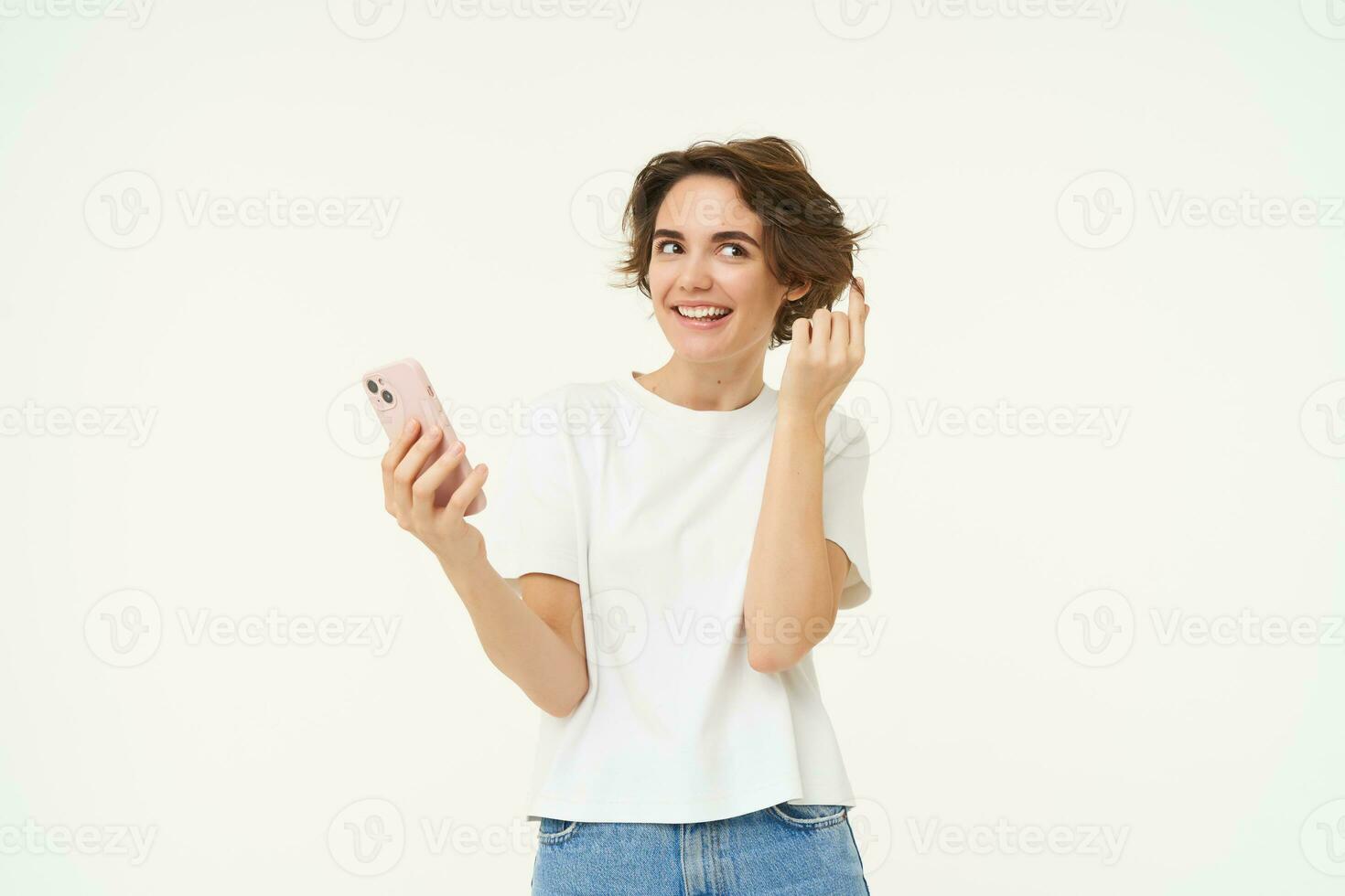 Technology and people. Happy brunette woman with mobile phone, smiling and laughing, standing over white background photo