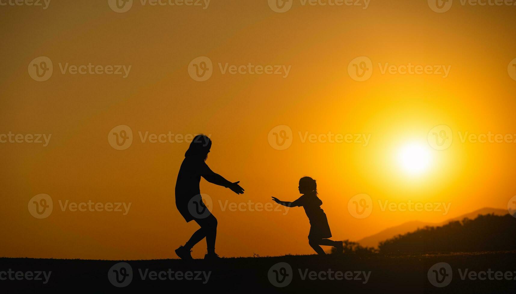 silueta, contento madre y hija corriendo a abrazo cada otro en el campo césped a puesta de sol en el noche. amor familia actividad relajarse concepto. foto