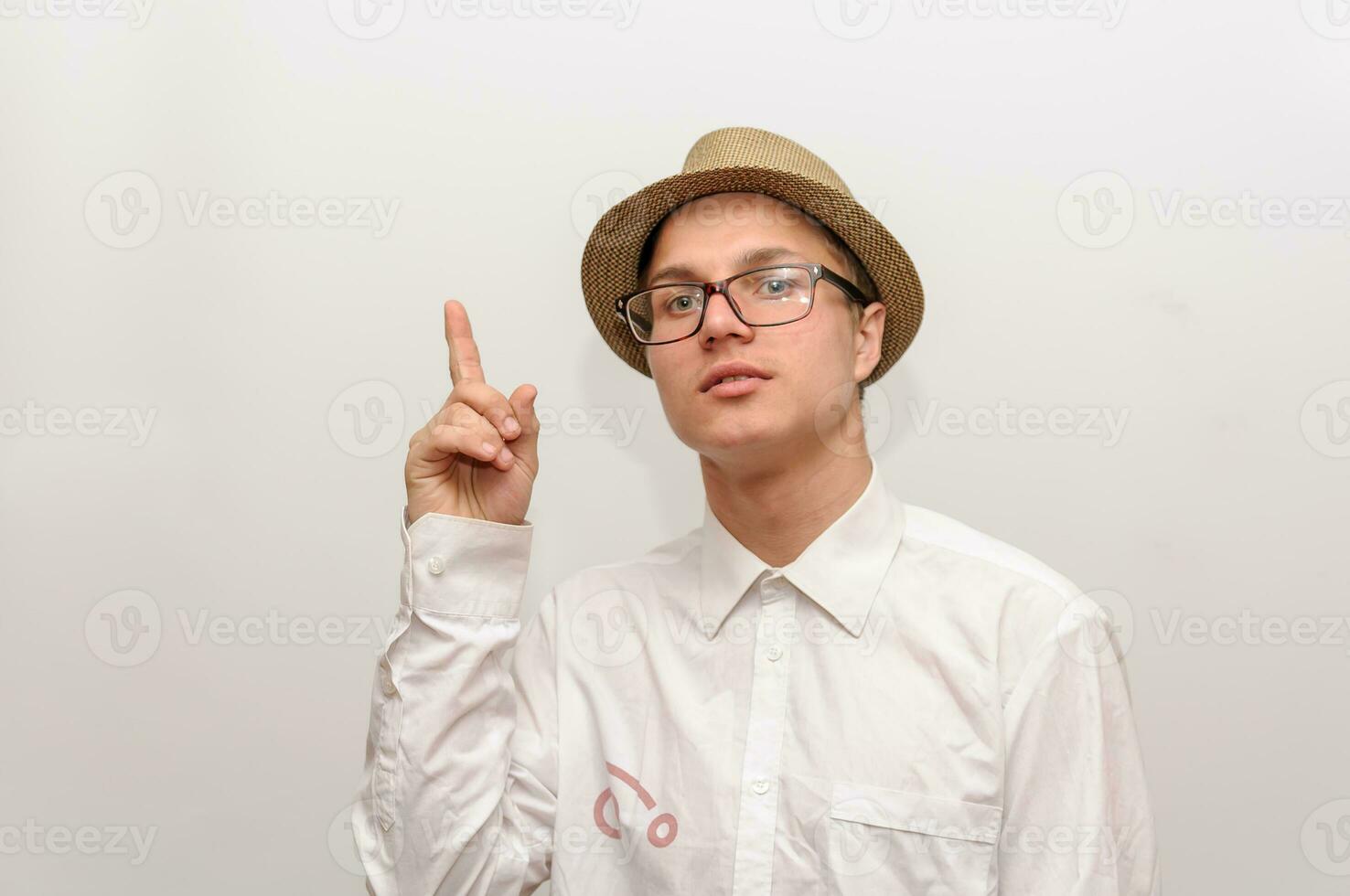 The young guy in glasses and a hat points a finger to the top. photo