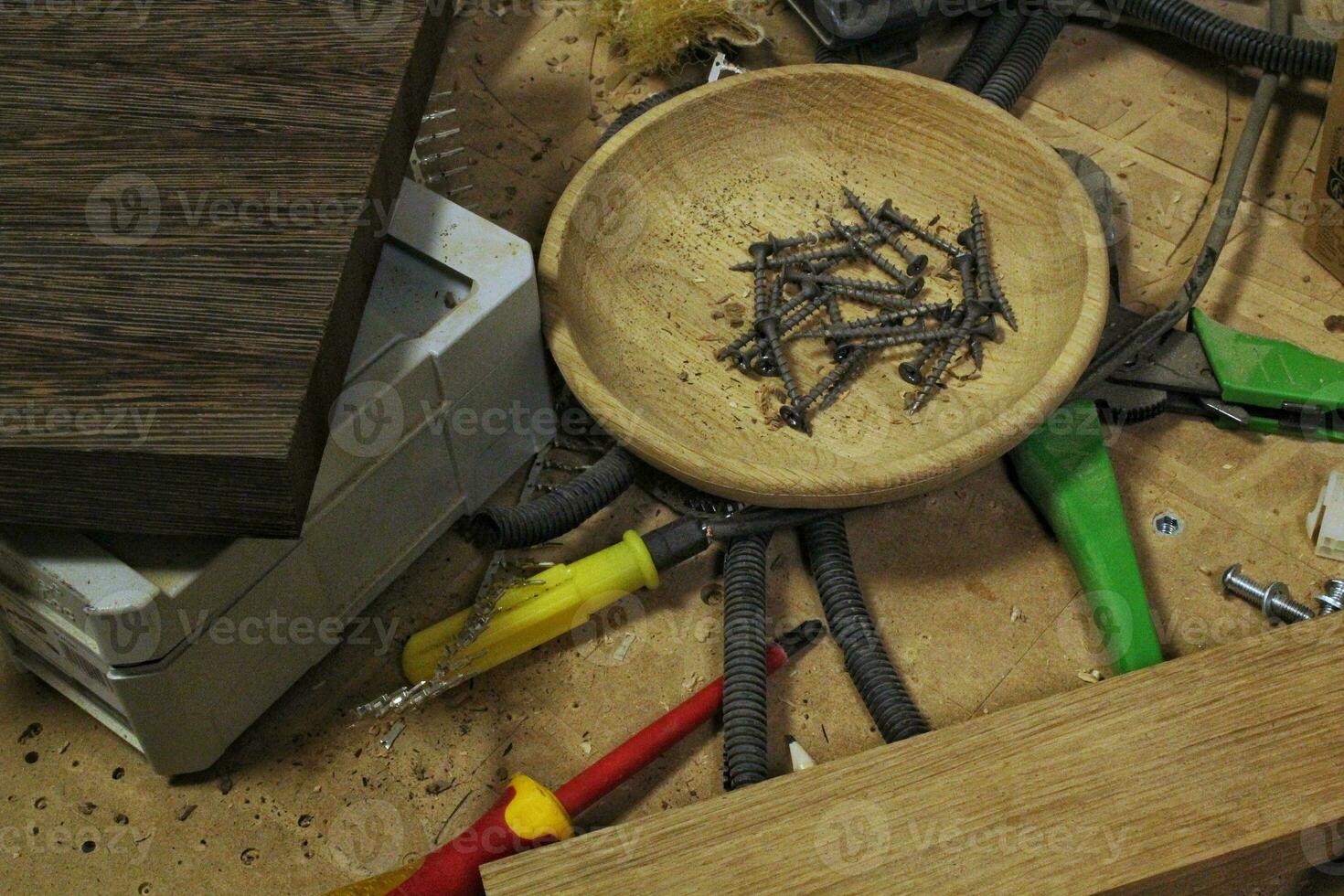 Craft carpentry workshop with variety of wooden pieces and planks, hand tools and wooden work bench in the foreground. Joinery with workbench and lots of wood. Carpenters table with furniture details photo