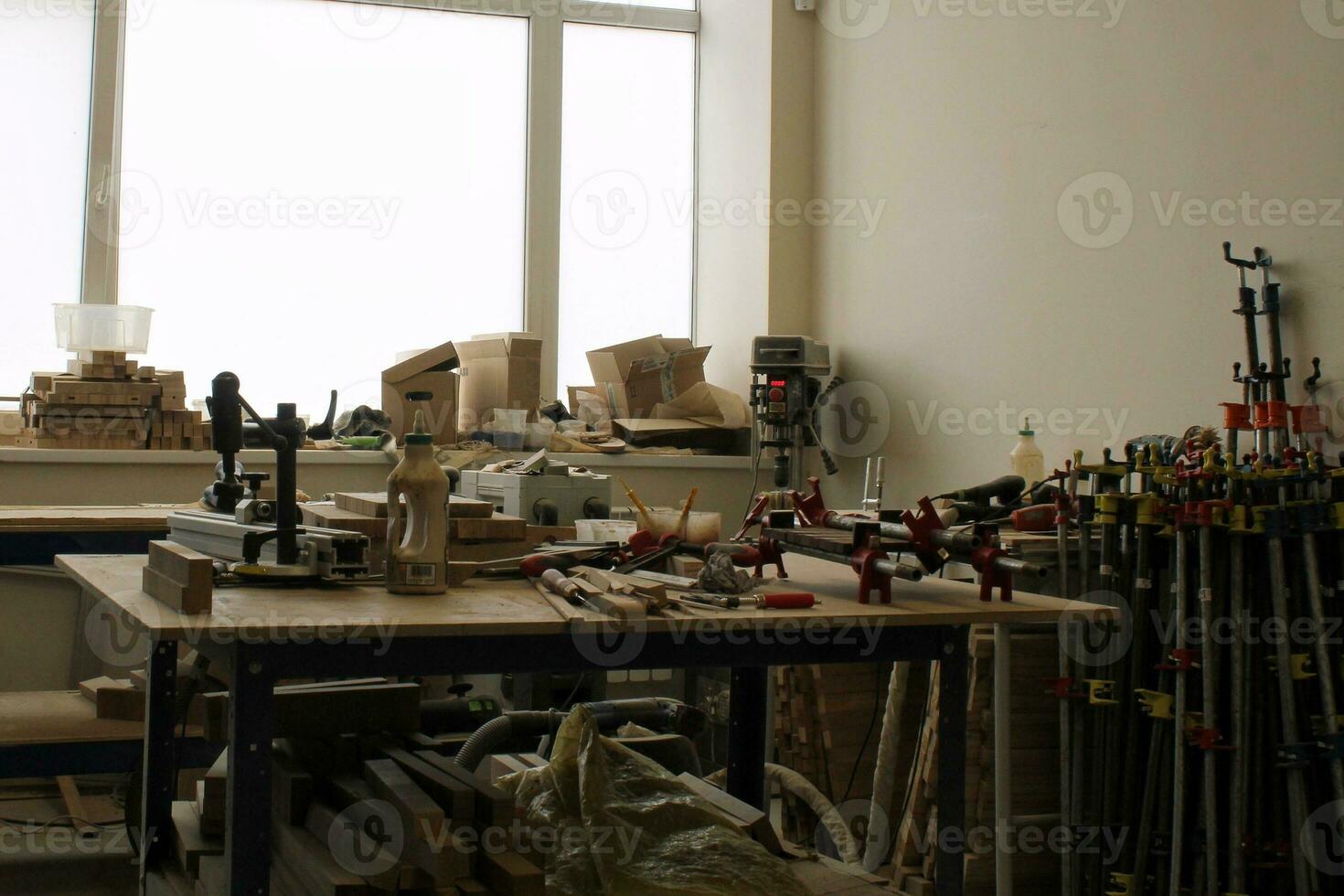 Craft carpentry workshop with variety of wooden pieces and planks, hand tools and wooden work bench in the foreground. Joinery with workbench and lots of wood. Carpenters table with furniture details photo