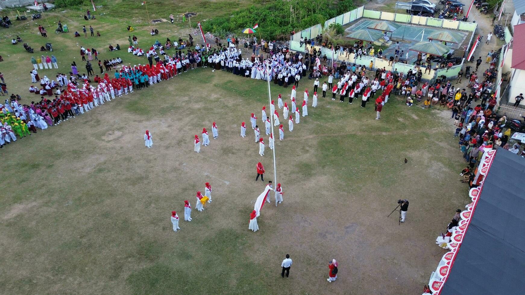 Aerial view of Indonesian flag lowering ceremony witnessed by villagers. Indonesia Independence Day photo