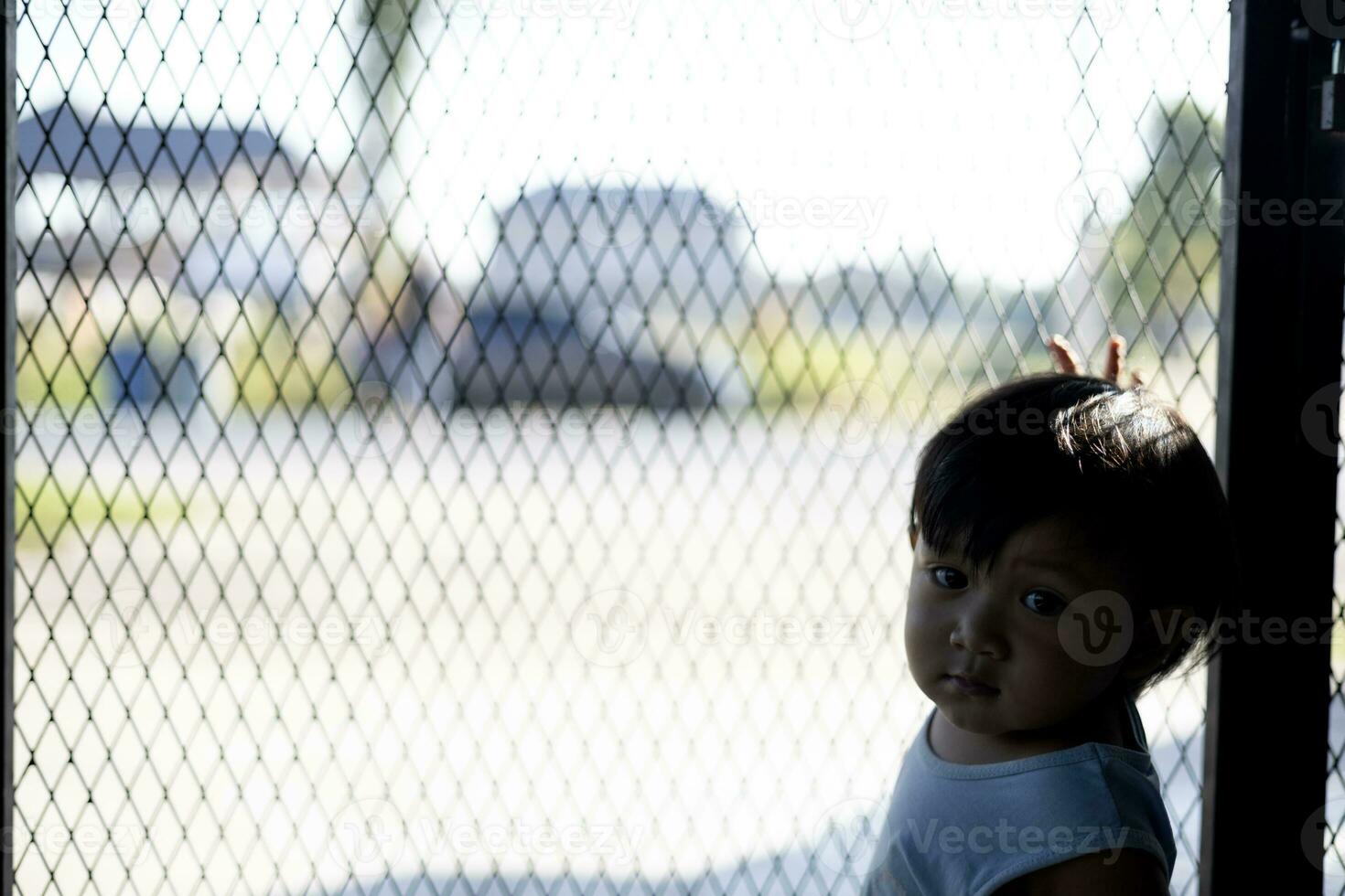 The Boy Holds On To The Iron Fence With His Hand. photo