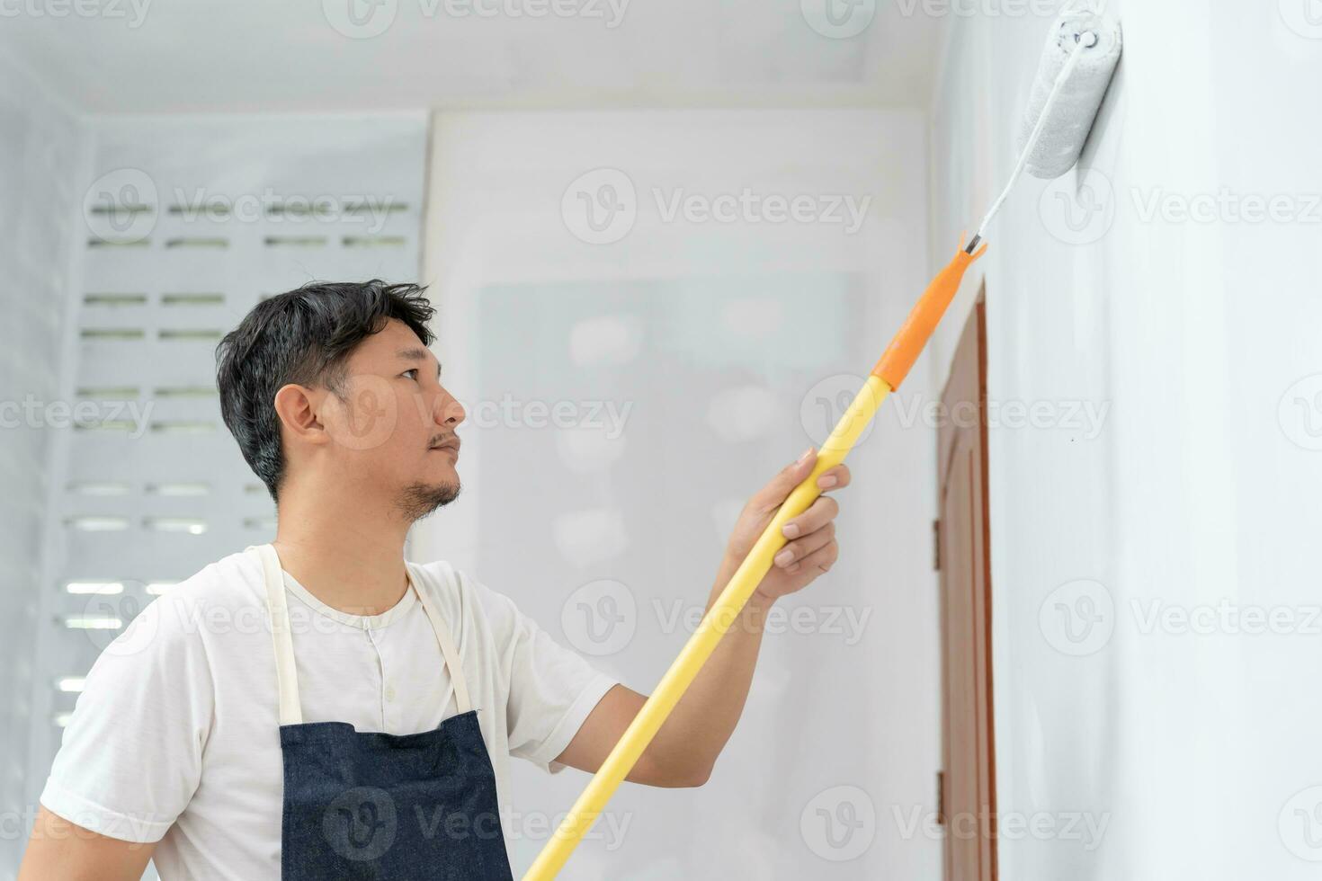 painter man, brush in hand for products to restore and paint the wall, indoor the building site of a house, wall during painting, renovation, painting, contractor, Architect, construction worker photo