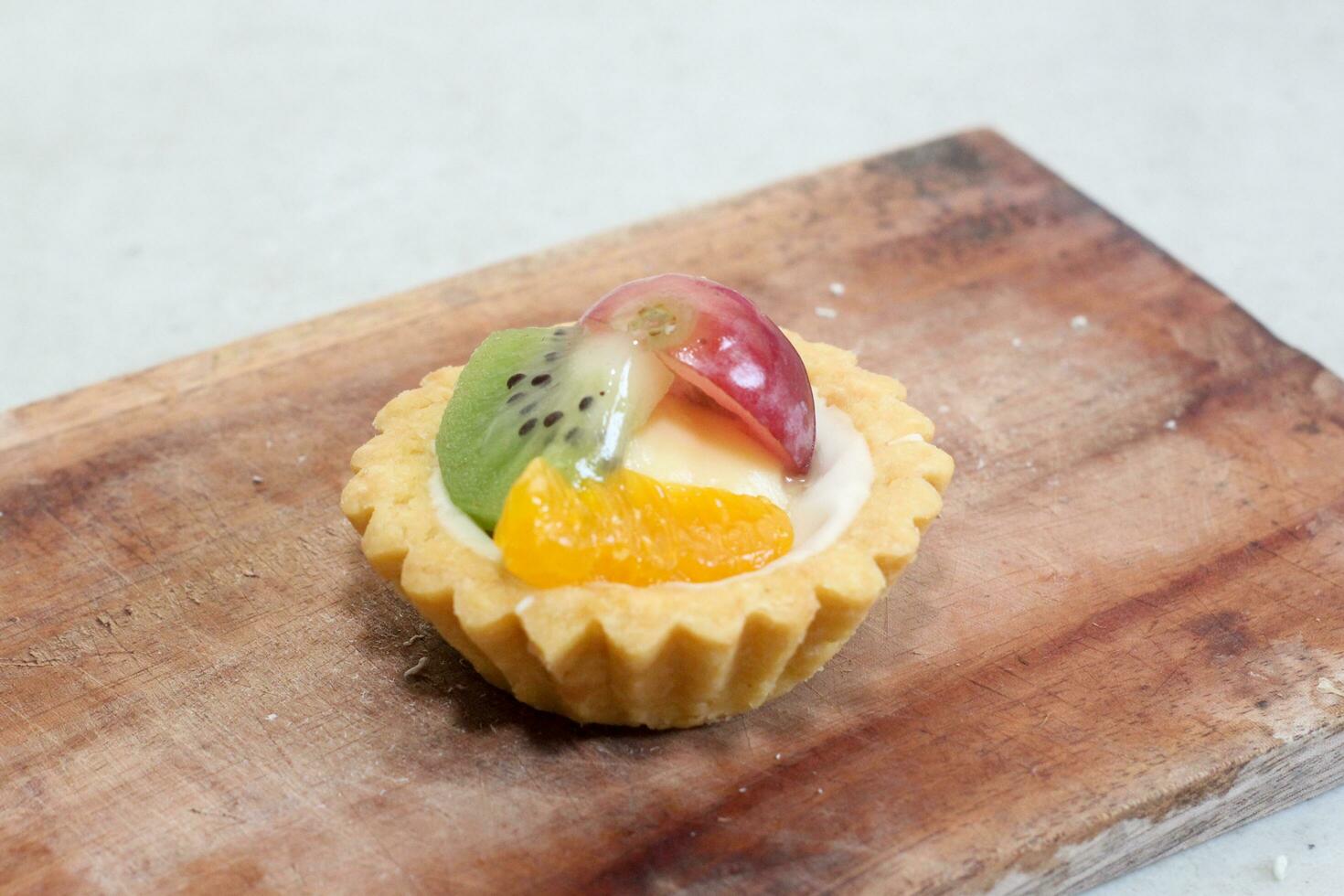 Fruit pie healthy dessert dish with cream cheese filling, garnished with kiwi, grapes, and oranges photo