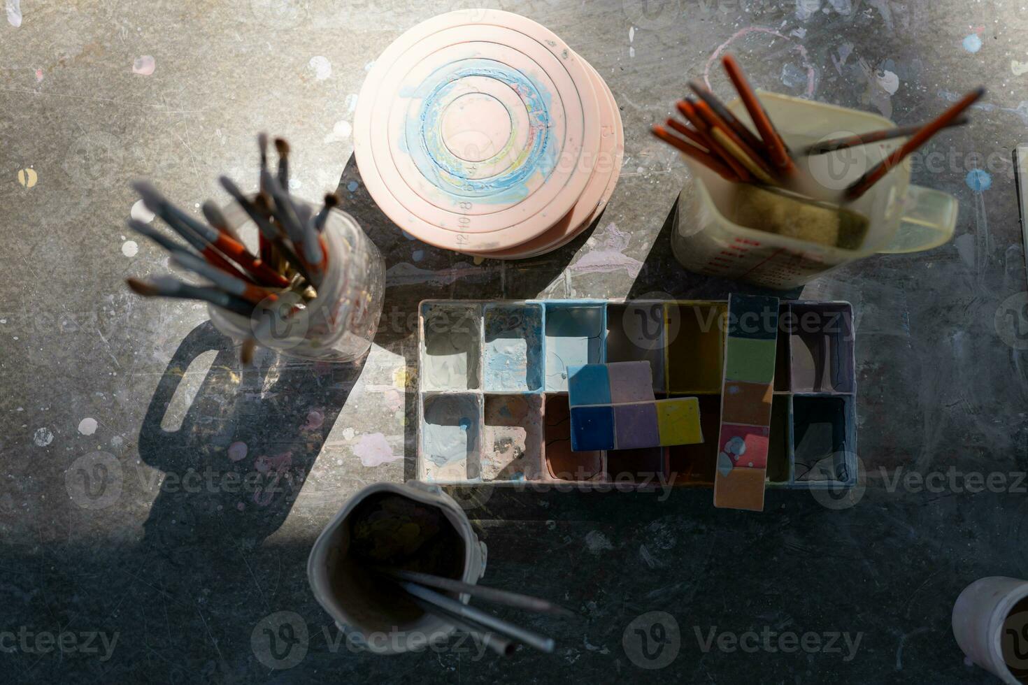 Paint brushes in glass jar on wooden table in the garden for preparing to paint pottery. photo