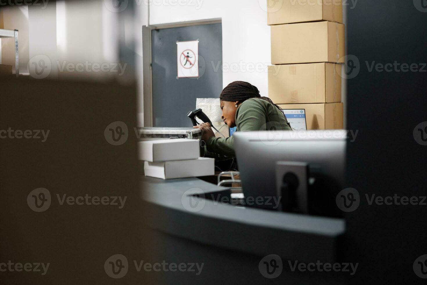 Storage room manager checking metallic box before delivery order to customer, analyzing products quality control in storehouse. African american woman wearing industrial overall during goods inventory photo