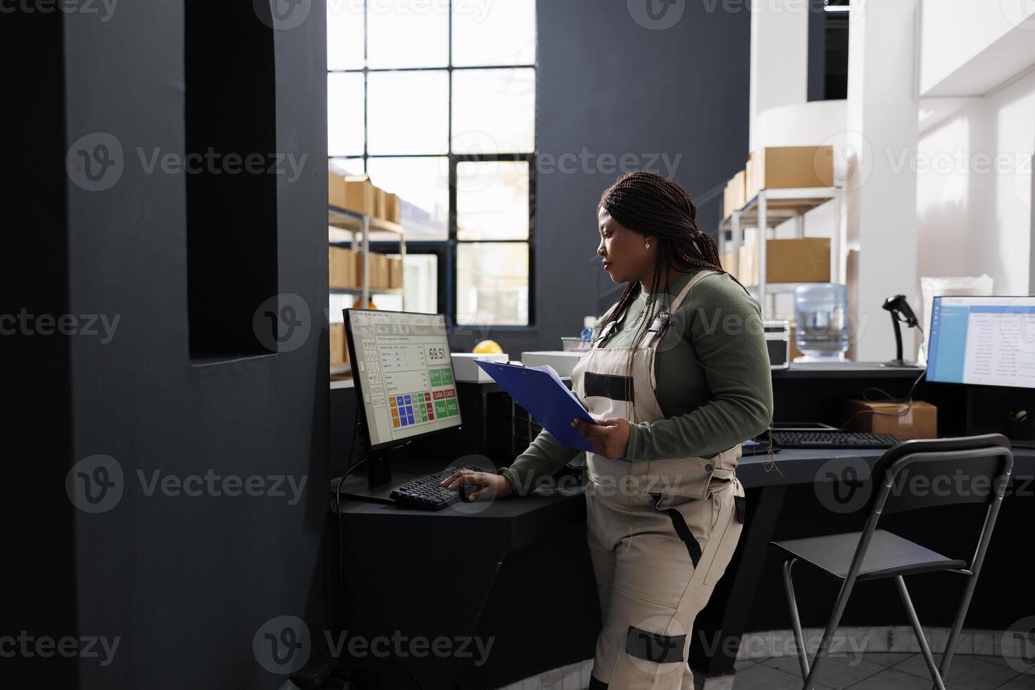 African american worker checking merchandise logistics on computer, working at customers orders in warehouse. Stockroom supervisor standing at counter desk preparing packages in storehouse photo