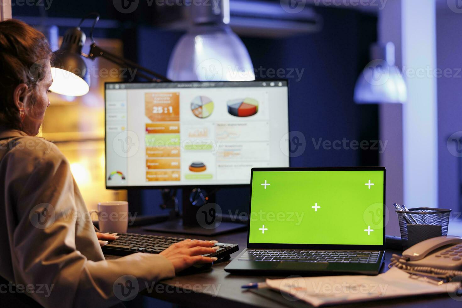 Businesswoman typing marketing strategy while analyzing with green screen chroma key mock up laptop computer with isolated display. Executive manager working overtime at investment plan photo