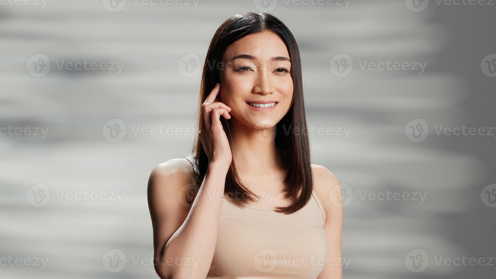 Asian lady doing empowering beauty campaign for self love, promoting natural skincare routine in studio. Young flawless model being gentle and elegant, feeling confident about imperfections. photo