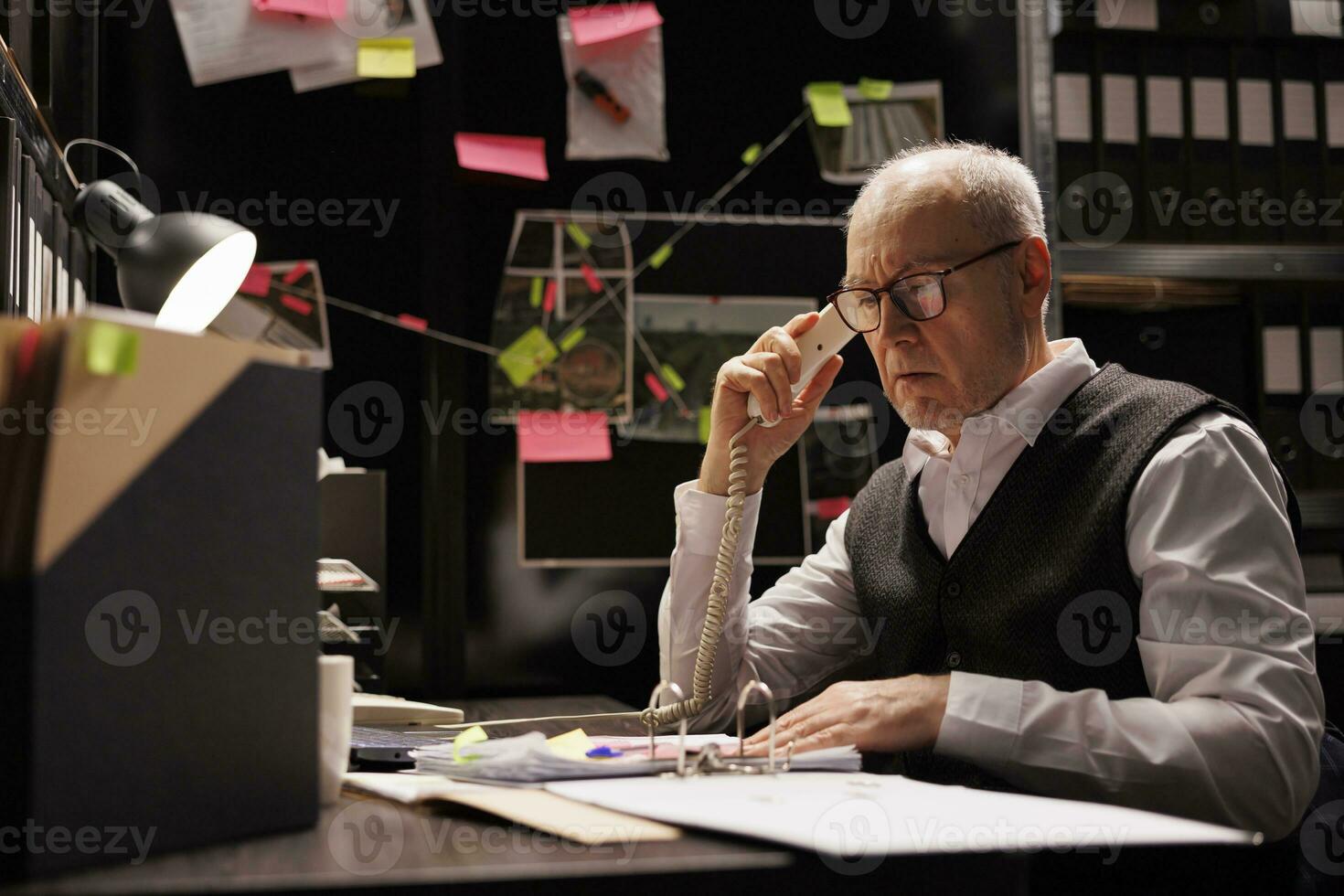 Elderly police officer thinking at solution to catch supect, working overhours at criminal case in dark room. Overworked private detective checking crime scene evidence, looking at victim report photo