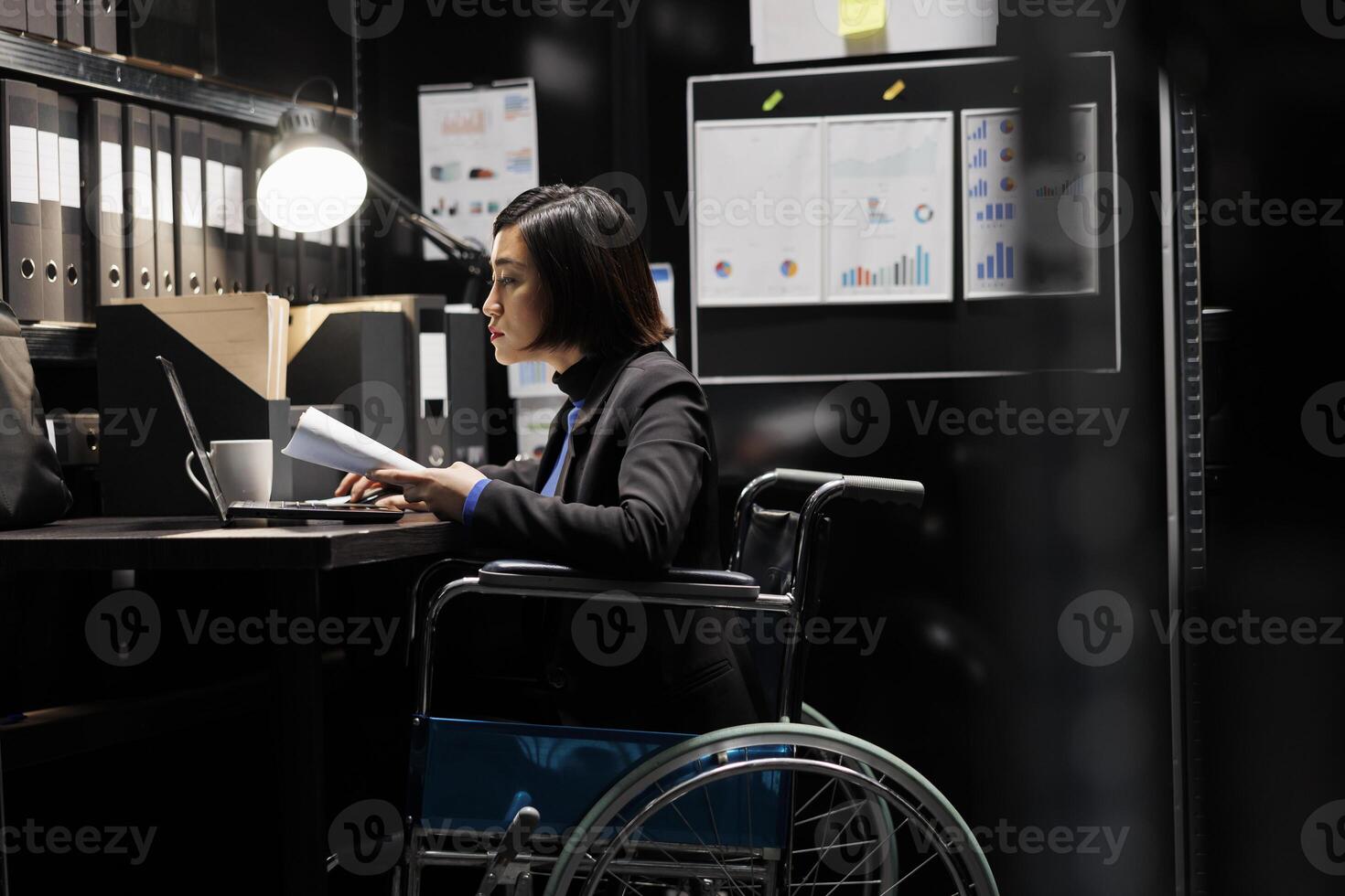 Paralyzed businesswoman employee in wheelchair checking bookkeeping analytical data documents. Accountant with disability in business company file cabinet depository filled with charts and folders photo