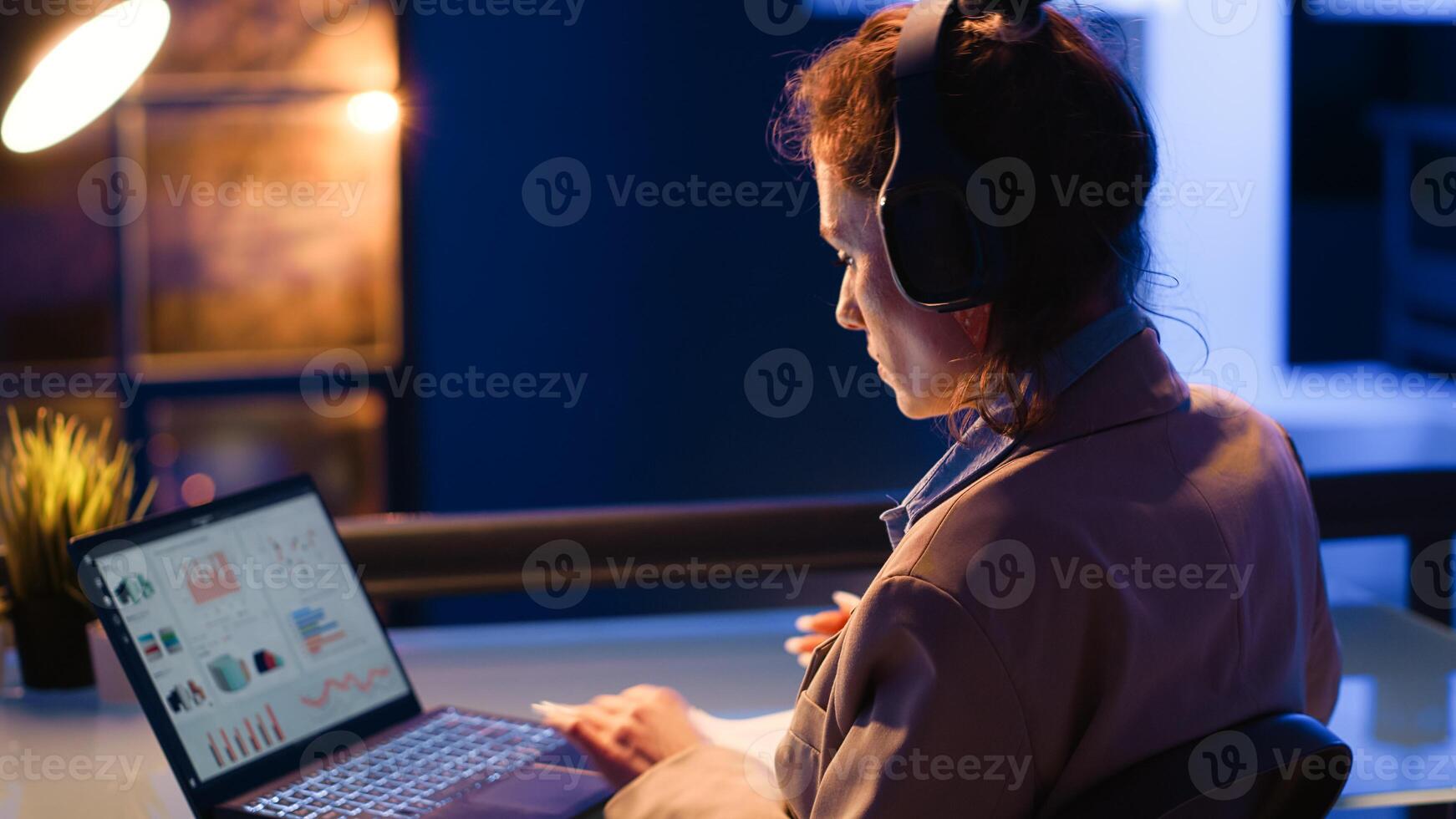 Careful manager analyzing e commerce diagrams report on laptop, typing financial report to increase profit. Young woman working at night time on investment plan with statistics and analytics. photo