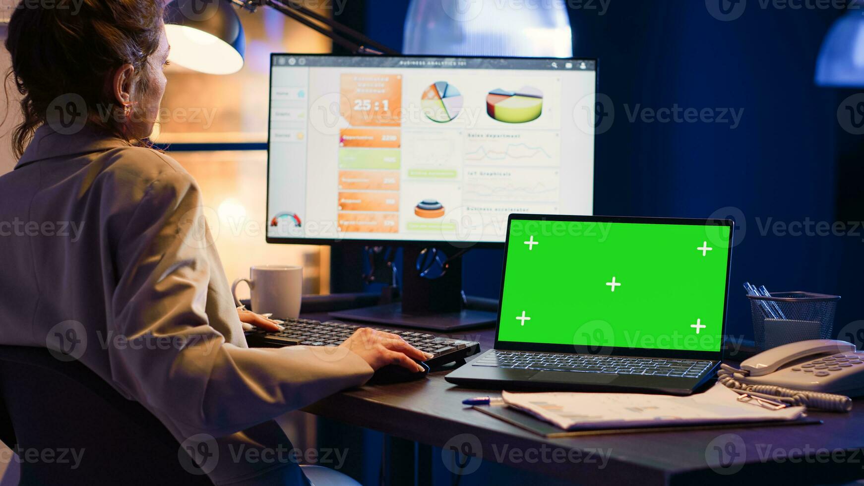 Business manager working with greenscreen on laptop, sitting at desk and looking at isolated mockup template. Woman advisor using computer with chroma key display, copyspace screen. photo