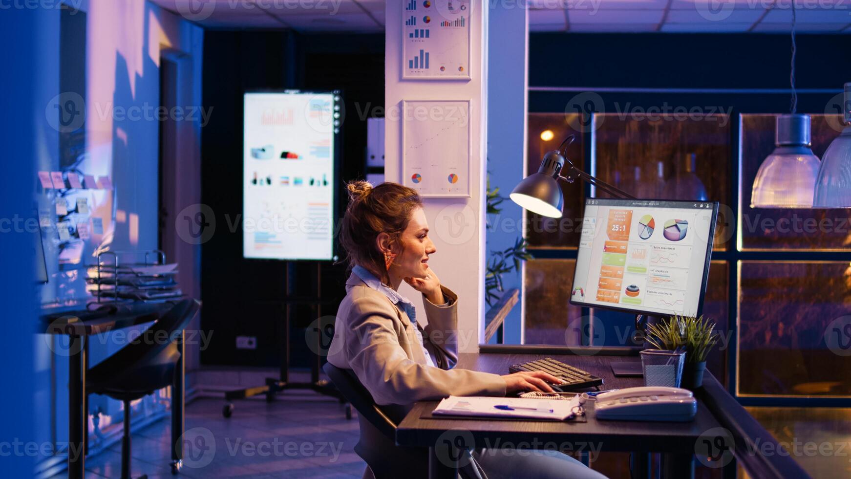Entrepreneur working on financial growth late at night, planning business report with online statistics to finish project. Female advisor checking analytics after hours. Handheld shot. photo