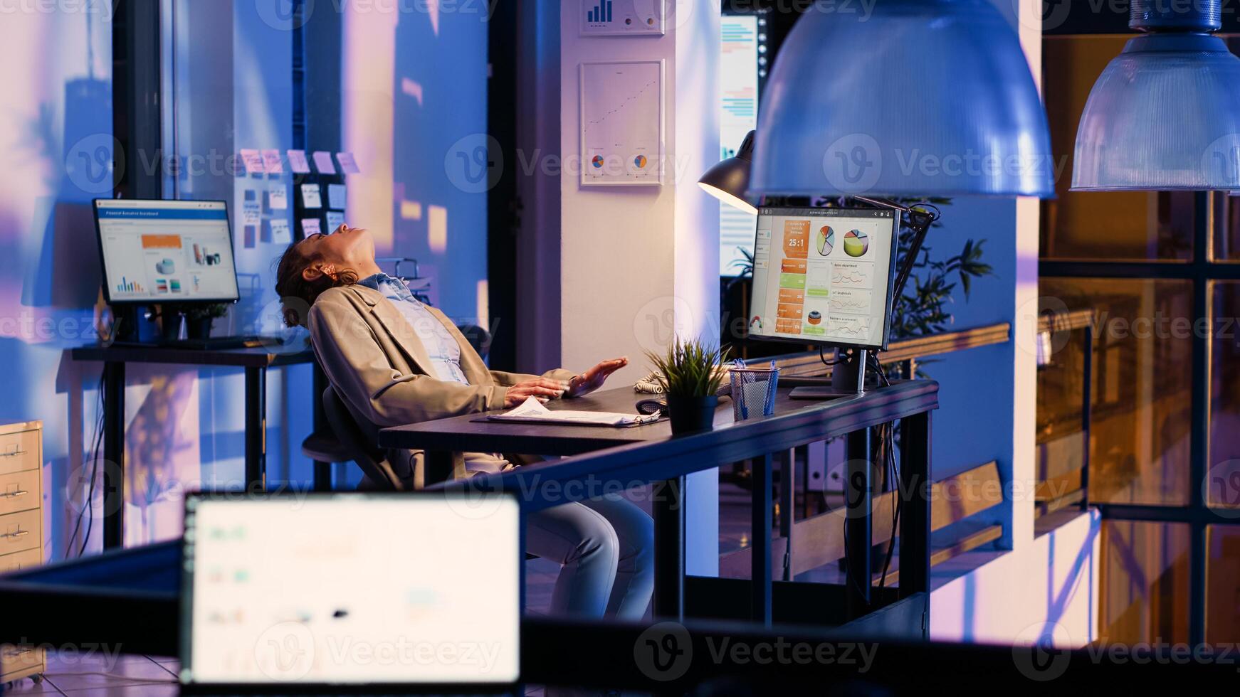 Young adult feeling tired working overtime on report yawning and working on increasing profit. Sleepy exhausted employee planning investment for business growth and development. photo